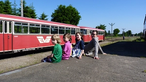 Drei Kinder und ein Erwachsener sitzen auf am Bahnhof Gnarrenburg und betrachten den alten Moorexpress. © Udo Fischer
